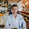 Man in a blue suit smiling at the bar.