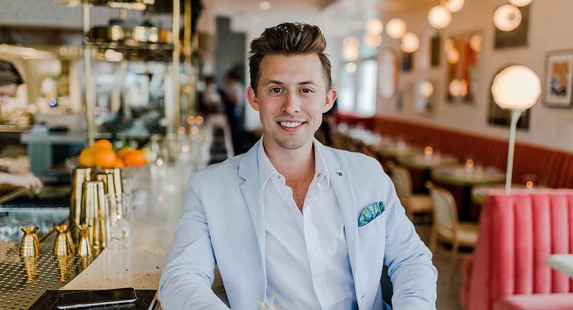 Man in a blue suit smiling at the bar.