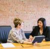 Two women discussing work in an office.