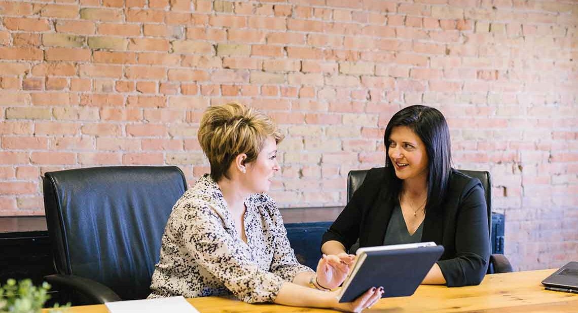 Two women discussing work in an office.