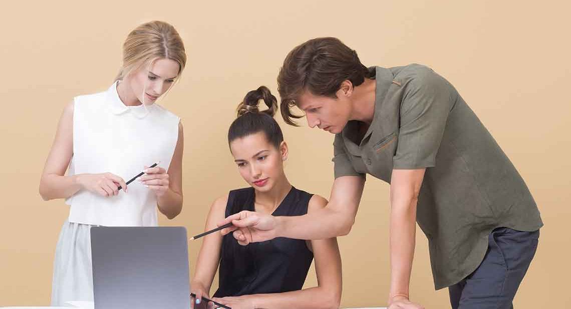 Three people working together on a laptop.