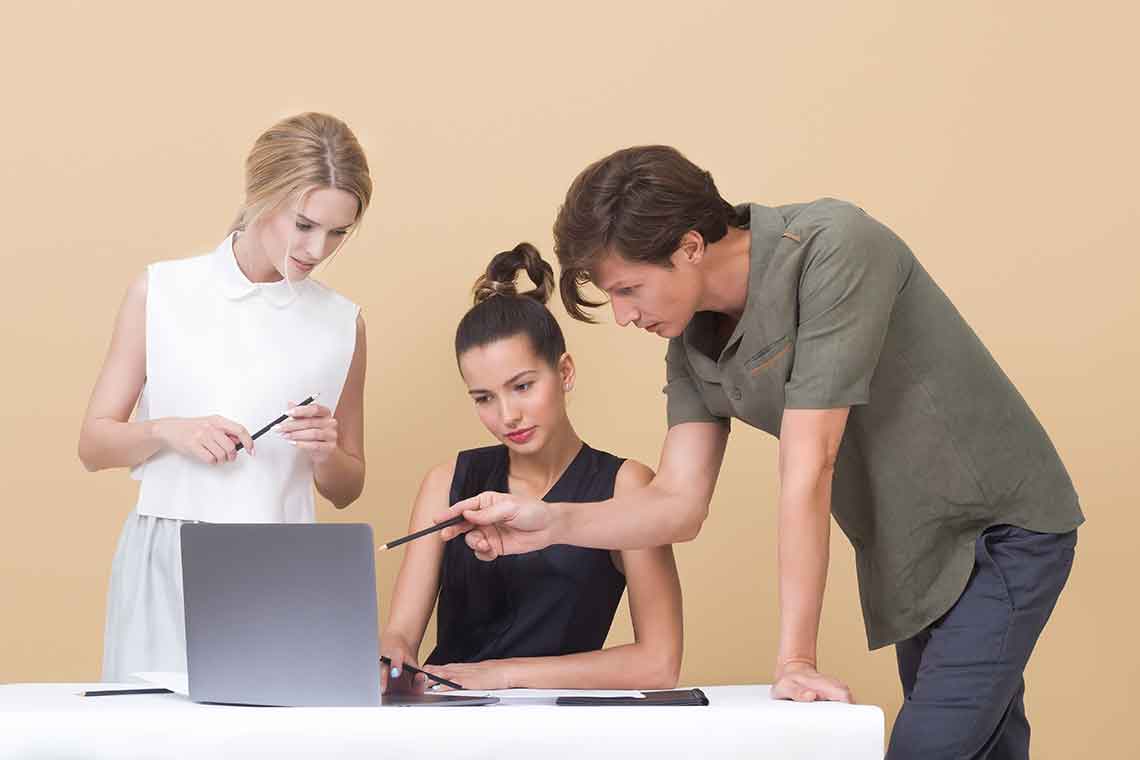 Three people working together on a laptop.