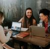 Three friends working on laptops and smiling.