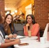 Four women chat at a cafe table.