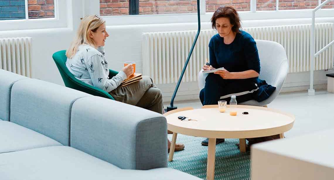 Two women talking in a modern office.