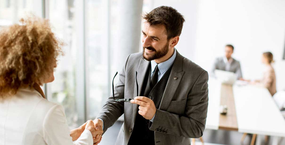 Man and woman shaking hands in office.