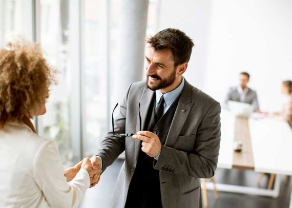 Man and woman shaking hands in office.