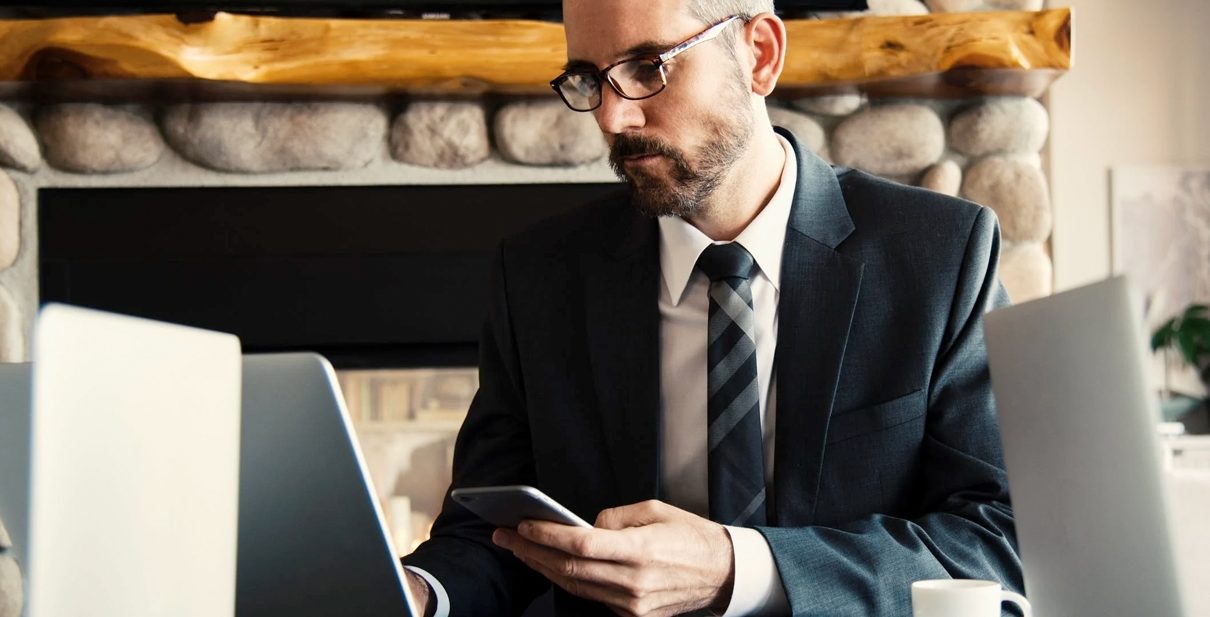 Businessman working on laptop with phone.