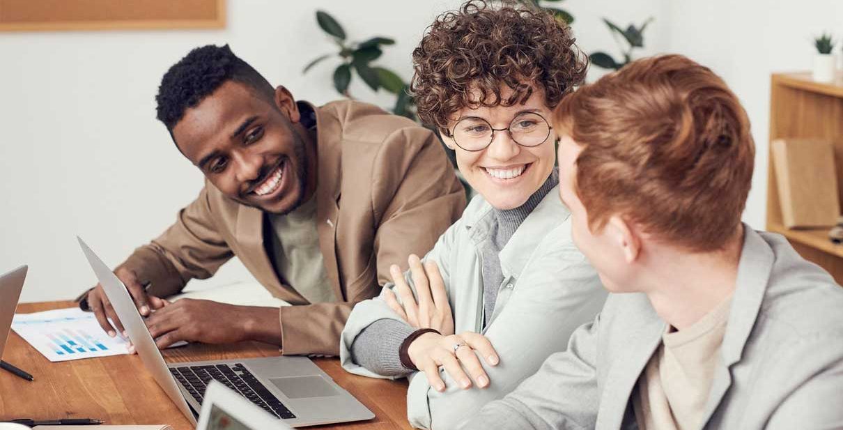 Three colleagues smiling and working together.