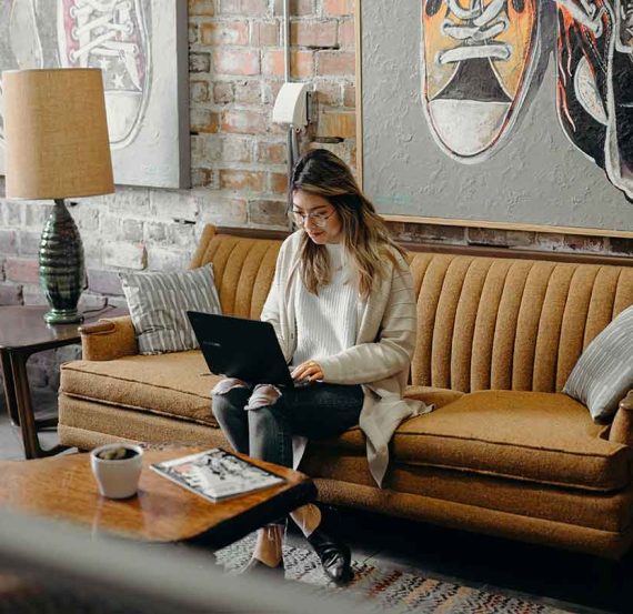 Woman working on laptop on a couch.