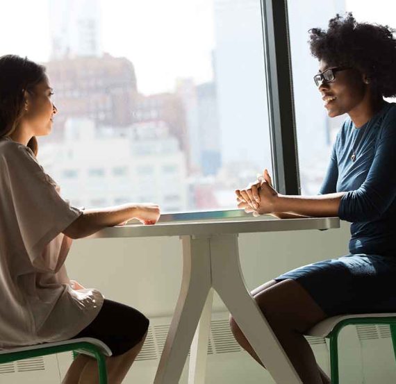 Two women sitting at a table, talking.