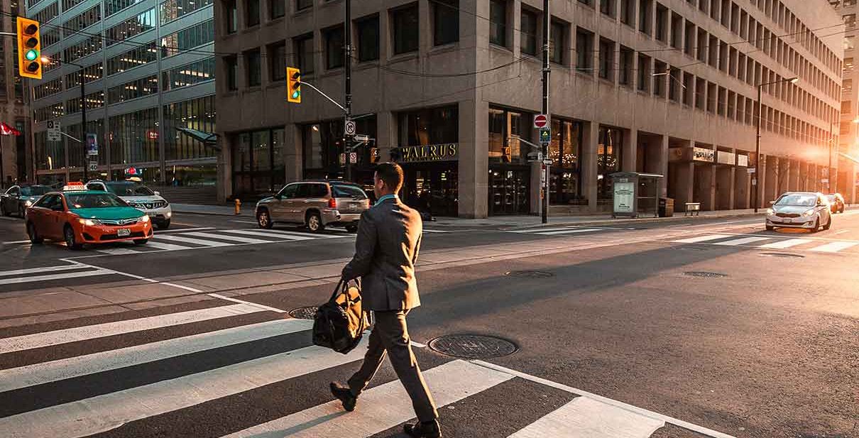 Man crossing city street with bag.