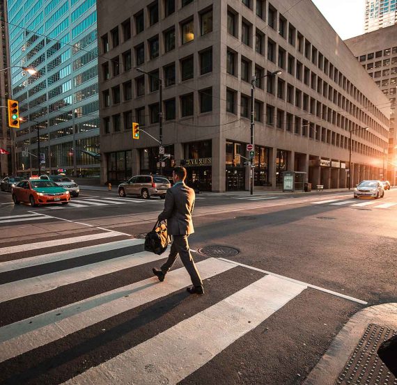 Man crossing city street with bag.