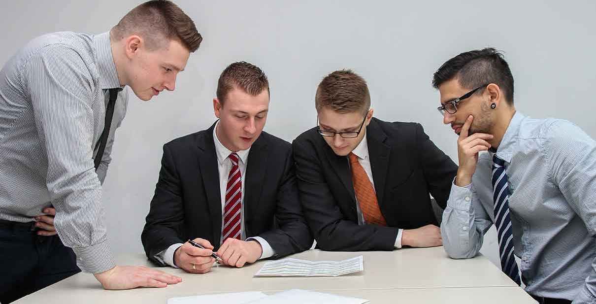 Four men reviewing paperwork in office.