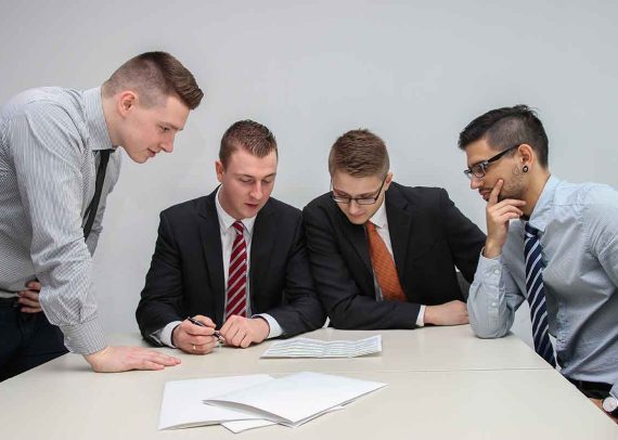 Four men reviewing paperwork in office.