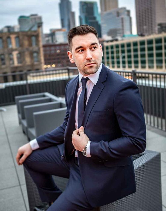 Man in suit sitting on a bench in the city.