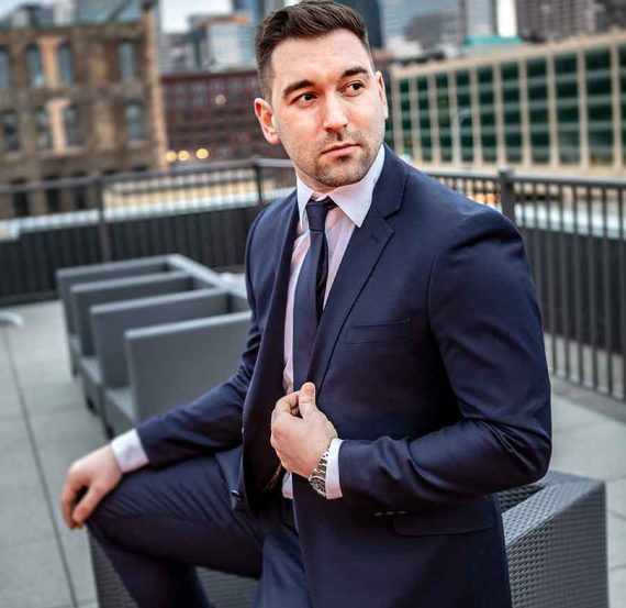 Man in suit sitting on a bench in the city.