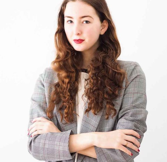 Woman in a plaid blazer with arms crossed.