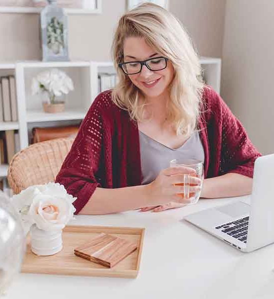 Woman working on laptop with tea.