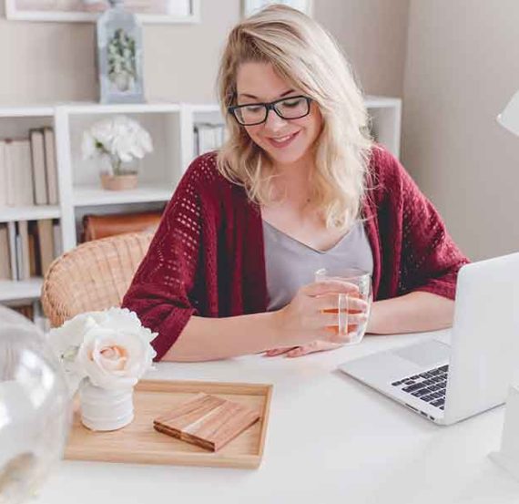 Woman working on laptop with tea.