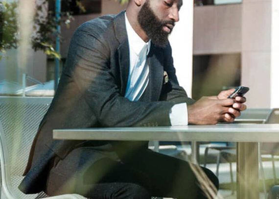 Man in suit using phone at a table.