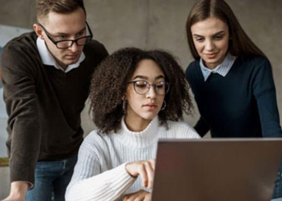 Three people looking at a laptop.