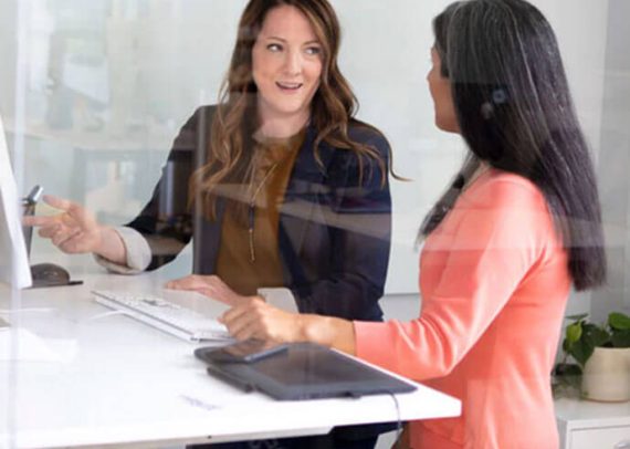 Two women working at a standing desk.