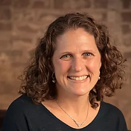 Smiling woman with brown hair and blue eyes.