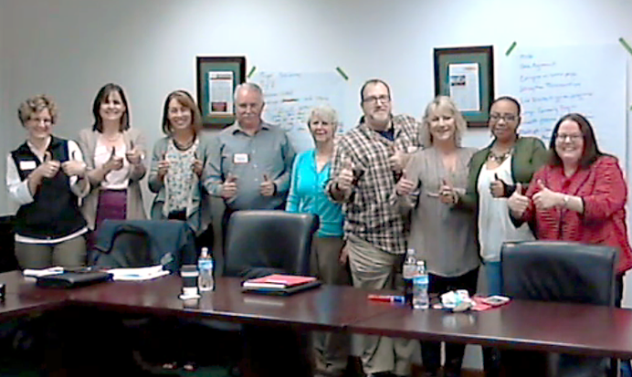 Group of people giving thumbs up in a meeting room.