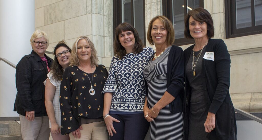 Group of six women smiling for photo.